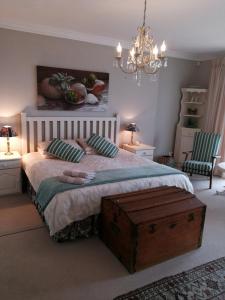 a bedroom with a large bed and a chandelier at Sit-en-Kyk in Hermanus