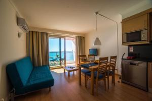 a living room with a table and a kitchen with a view of the ocean at Sezimbra in Sesimbra