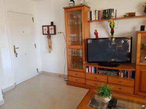 a living room with a television on a wooden entertainment center at Cascadas de la Marina in Denia