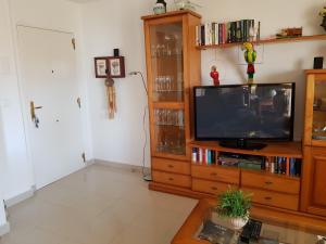 una sala de estar con TV en un centro de entretenimiento de madera en Cascadas de la Marina, en Denia