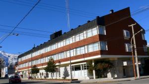 un gran edificio en una calle con una montaña en Hotel Tehuelche, en Esquel