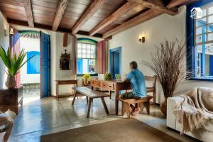 a woman sitting at a table with a laptop in a room at Casa no Centro Histórico com 3 Quartos in Paraty