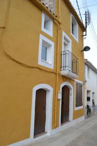 Edificio amarillo con 2 puertas y balcón en Cal Llorenç, en Sant Pere Sacarrera