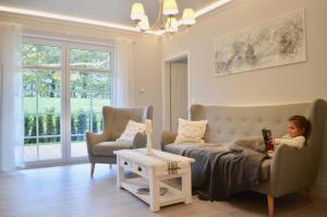 una niñita sentada en un sofá en una sala de estar en Villa Strandblick 10, en Zingst