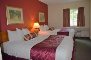 two beds in a hotel room with red walls at Baymont by Wyndham Wichita East in Wichita