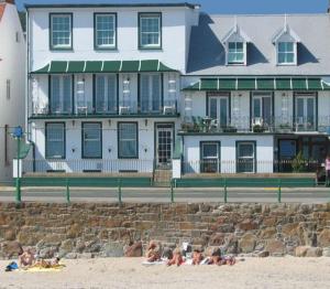 a group of people laying on the beach in front of a building at Havelock Guesthouse in Saint Helier Jersey