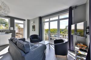 uma sala de estar com um sofá, cadeiras e janelas em Belle vue em Montsoreau