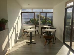 a row of tables and chairs in a room with windows at Hostal CKAIR in Bahia Inglesa