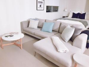 a living room with a white couch and blue pillows at WoodyHanger Lodge in Whitianga