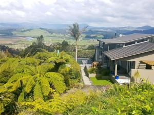 a house with a view of a garden at WoodyHanger Lodge in Whitianga