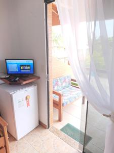 uma sala de estar com uma televisão e uma porta de vidro deslizante em Pousada Suites do Santinho em Florianópolis