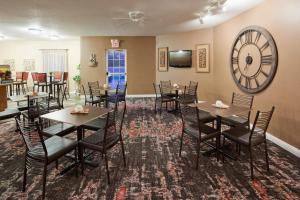 a dining room with tables and chairs and a clock at GrandStay Residential Suites Hotel - Eau Claire in Eau Claire
