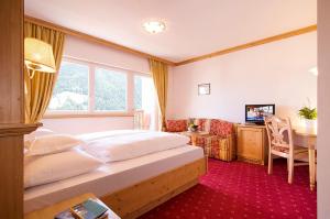 um quarto com uma cama, uma secretária e uma televisão em Hotel Sonne em Stelvio
