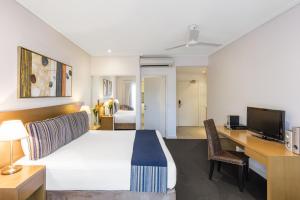 um quarto de hotel com uma cama grande e uma secretária em Oaks Broome Hotel em Broome