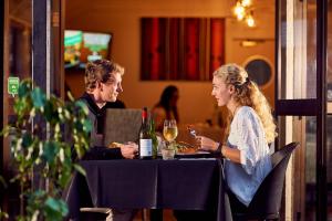 a man and a woman sitting at a table with wine at Mount Richmond Hotel in Auckland