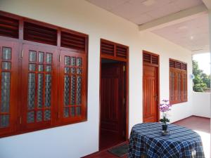 a room with wooden doors and a table with a table cloth at Bloom Guest House in Mirissa