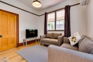 sala de estar con sofá y TV en Rosehaven Cottage en Hobart
