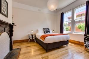 1 dormitorio con 1 cama y chimenea en Rosehaven Cottage en Hobart