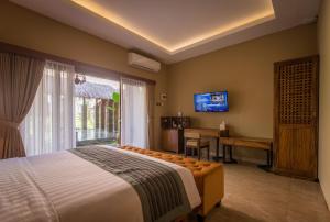 a bedroom with a bed and a desk and a television at ILA Villa Ubud in Ubud