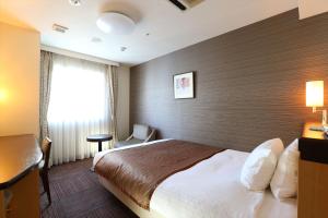a hotel room with a large bed and a window at Hotel Hokke Club Sapporo in Sapporo