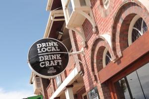 a drink local drink craft sign on the side of a building at Great Ocean Road Brewhouse Apollo Bay in Apollo Bay