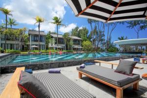a resort pool with a chaise lounge and an umbrella at Baba Beach Club Natai Luxury Pool Villa Hotel by Sri panwa - SHA Plus in Natai Beach