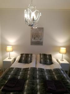 a bedroom with a bed with two lamps and a chandelier at RovaVisit Apartments Siljo in Rovaniemi