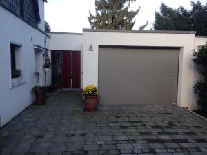 a garage door with a flower pot on a brick driveway at Arrive & Relax - Volkmar in Düsseldorf