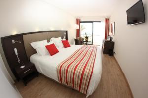 a bedroom with a large bed with red pillows at Hôtel Restaurant Splendid Camargue in Le Grau-du-Roi