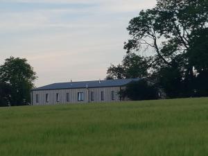 eine große weiße Scheune auf einem Feld mit Gras in der Unterkunft Oak & Hazel, Heath Row Barn in Overton