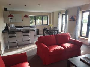 a living room with a red couch and a kitchen at Oak & Hazel, Heath Row Barn in Overton