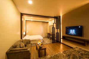 ein Wohnzimmer mit einem Sofa und einem Flachbild-TV in der Unterkunft Lily Hotel Suite Mubarraz in Al Hofuf