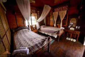 a bedroom with two beds in a log cabin at Huen Jam Rat in Mae Chaem