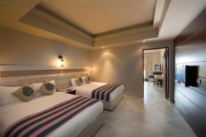 a hotel room with two beds and a television at Sunrise Arabian Beach Resort in Sharm El Sheikh