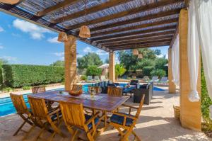 a patio with a wooden table and chairs and a pool at Ca Na Carme in Campos