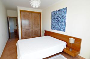 ラゴスにあるVue panoramique sur mer Condominio Do mar Lagosの白いベッドと木製のドアが備わるベッドルーム1室が備わります。