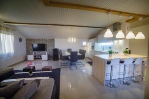 uma sala de estar em plano aberto e uma cozinha com um bar e cadeiras em Foric Apartments With Outdoor Heated Pool em Rab
