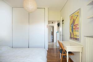 Schlafzimmer mit einem weißen Bett und einem Schreibtisch in der Unterkunft Varkiza Apartment in Varkiza