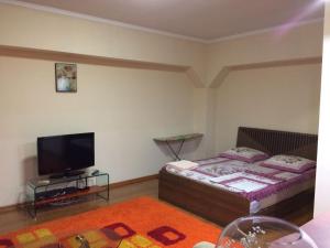 1 dormitorio con 1 cama y TV de pantalla plana en Квартира en Almaty
