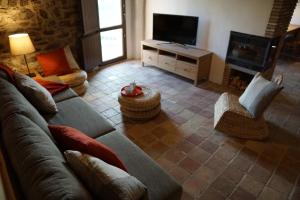 ein Wohnzimmer mit einem Sofa und einem TV in der Unterkunft Mas Roca Del Mill in Perafita