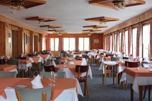 a dining room with tables and chairs and windows at Hotel de la Poste Verbier in Verbier