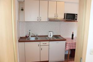 małą kuchnię z białymi szafkami i zlewem w obiekcie Dems w mieście Živogošće