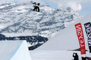 a snowboarder jumping off a ramp in front of a mountain at Apartment Leysin - Swiss Alps - Fully Renovated ! in Leysin