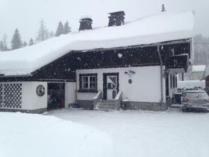 una casa cubierta de nieve con un coche aparcado delante en Ferienwohnung Susanne Hillbrand en Bad Aussee