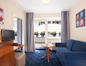 科隆的住宿－多姆卡拉斯酒店，客厅配有蓝色的沙发和电视