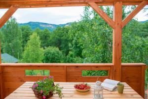 une terrasse couverte en bois avec une table et des fleurs. dans l'établissement DOMKI Kolonia Leśna z sauną, à Radków