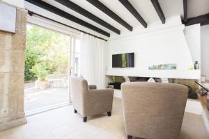 a living room with a tv and a chair at Villa Cala Padri in Font de Sa Cala