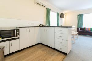 a kitchen with white cabinets and white appliances at Lincoln Cottage Motor Inn in Wagga Wagga