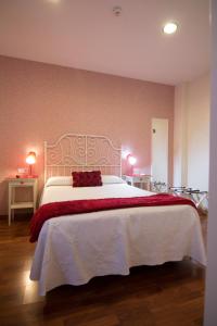 a bedroom with a large white bed with a red blanket at Hostal Paris in San Fernando