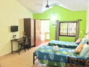 a room with two beds and a desk in it at John's Highland Comfort (Guest House) in Majorda